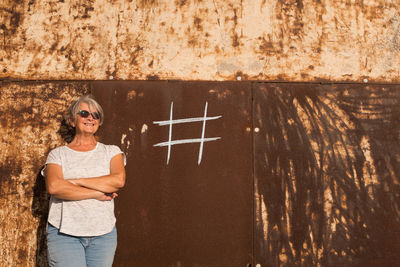 Portrait of smiling young woman standing against wall