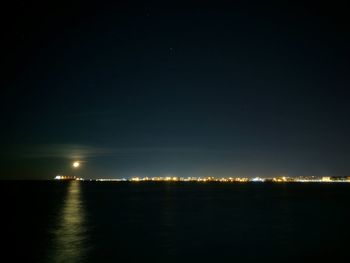 Illuminated sea against sky at night