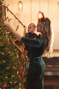 Side view of woman holding christmas tree