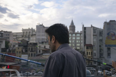 Rear view of man standing against buildings in city