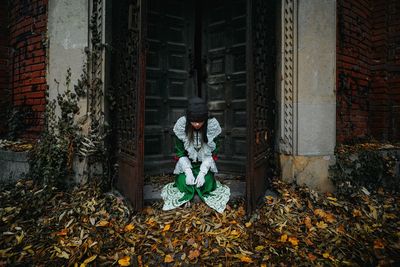 Woman in halloween costume standing by abandoned building