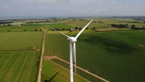 Scenic, drone view of wind turbine and agricultural fields against sky