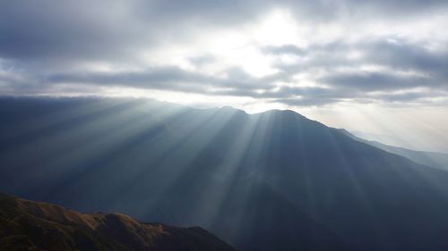 Low angle view of sunlight streaming through clouds