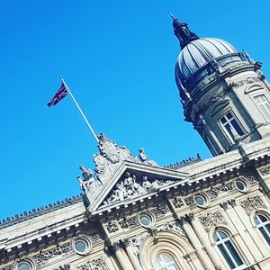 Low angle view of flag against clear blue sky