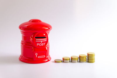 Close-up of red coins on table against white background