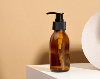 Brown glass bottle with black pump of cosmetic products on white table. natural organic spa 