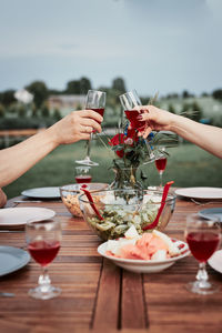 Couple making toast during summer outdoor dinner in a home garden. hands holding classes with wine