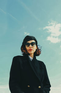 Portrait of young woman wearing sunglasses against sky