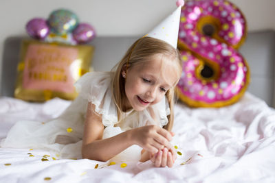 High angle view of girl playing with toys on bed at home