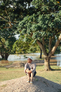 Full length of a man sitting on tree