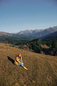 Rear view of woman sitting on mountain