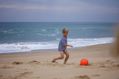 Young soccer player plays barefoot on the ocean shore. football, sport, passion. active lifestyle