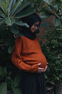 Young woman standing against plants