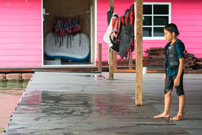 Young wet asian kid wearing life jackets getting ready to jump into the lake.