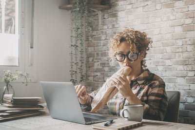 Young woman using mobile phone while sitting on table