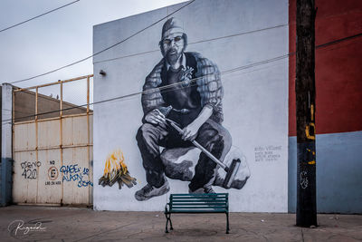 Statue of man holding umbrella against wall