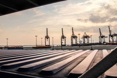 Factory by sea against sky during sunset