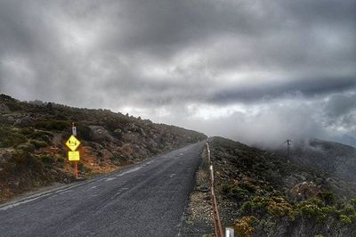 Country road against cloudy sky