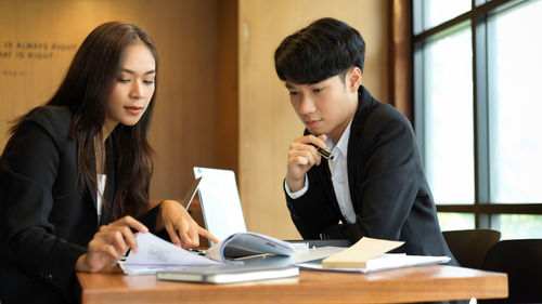 Young couple looking at camera while sitting on table