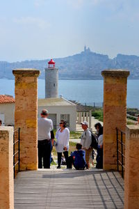 People on building by sea against sky