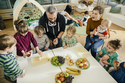 Group of children and teachers preparing fruit in kindergarten