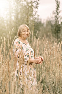 An elderly woman in the tall grass with spikelets. autumn.