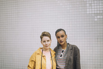 Portrait of lesbian couple standing together in front of wall