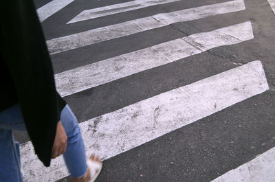 Low section of man walking on zebra crossing