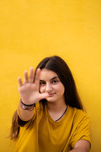 Portrait of young woman against yellow background