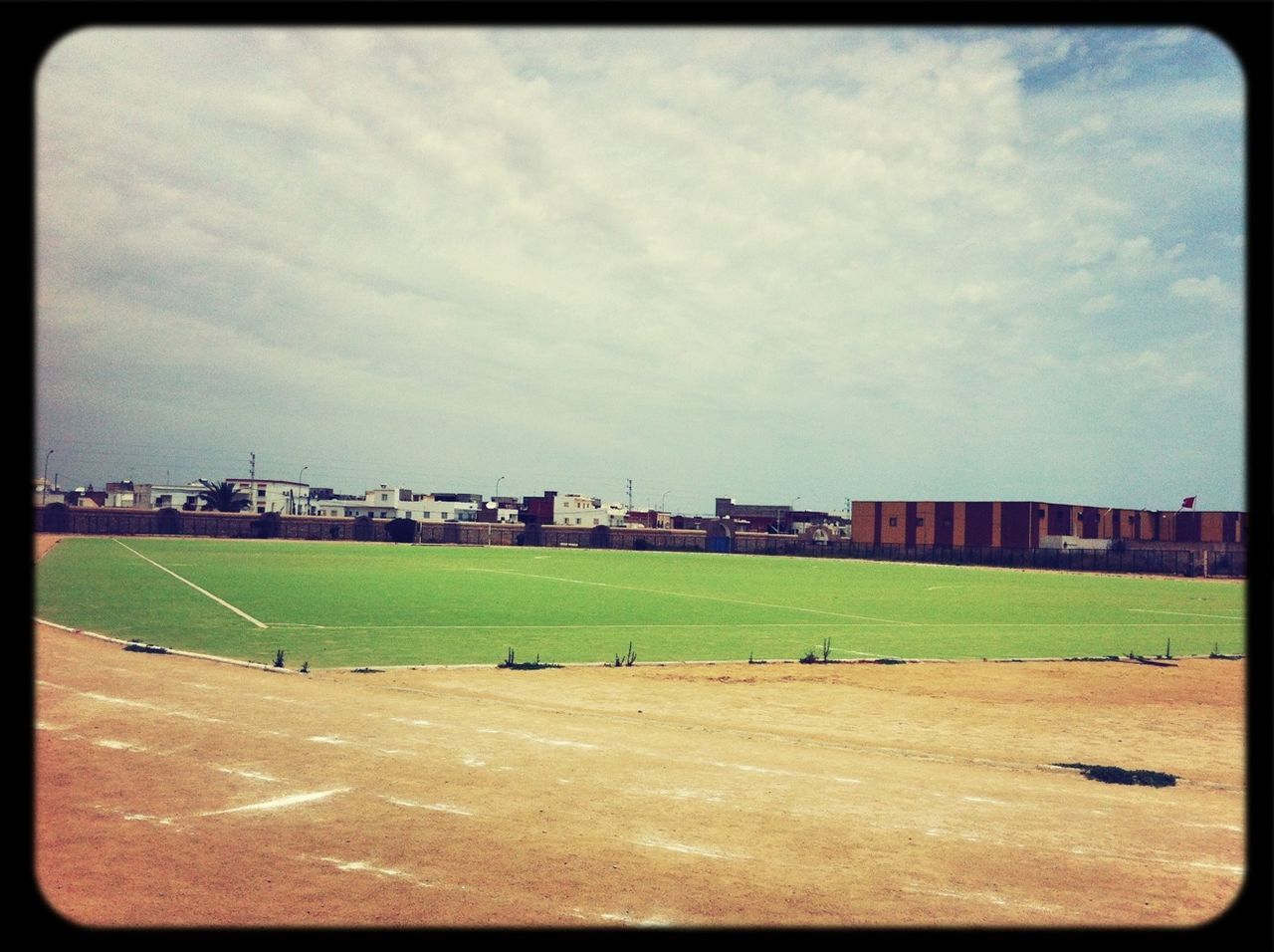 grass, building exterior, sky, transfer print, architecture, built structure, field, auto post production filter, cloud - sky, grassy, landscape, cloudy, road, cloud, green color, day, city, sport, outdoors, transportation