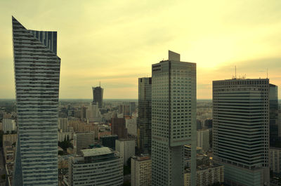 Modern buildings in city against sky during sunset