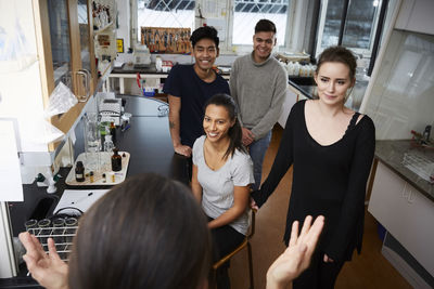 High angle view of female teacher explaining to happy multi-ethnic students at chemistry laboratory