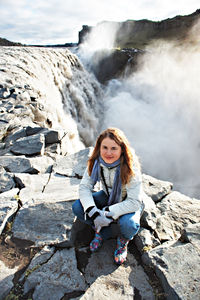 Portrait of young woman sitting on rock