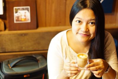 Portrait of a smiling young woman drinking glass