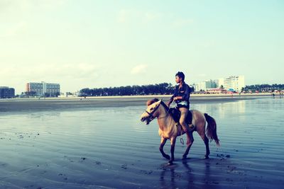 Man with dog on shore against sky