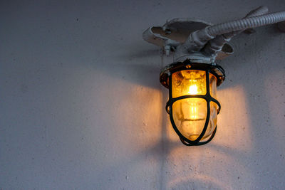 Low angle view of illuminated light bulb mounted on wall