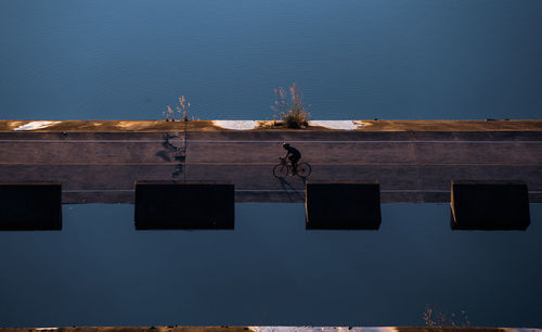 High angle view of man riding bicycle amidst lake on road