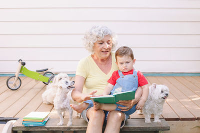 Happy senior woman sitting with grandson and dog outdoors