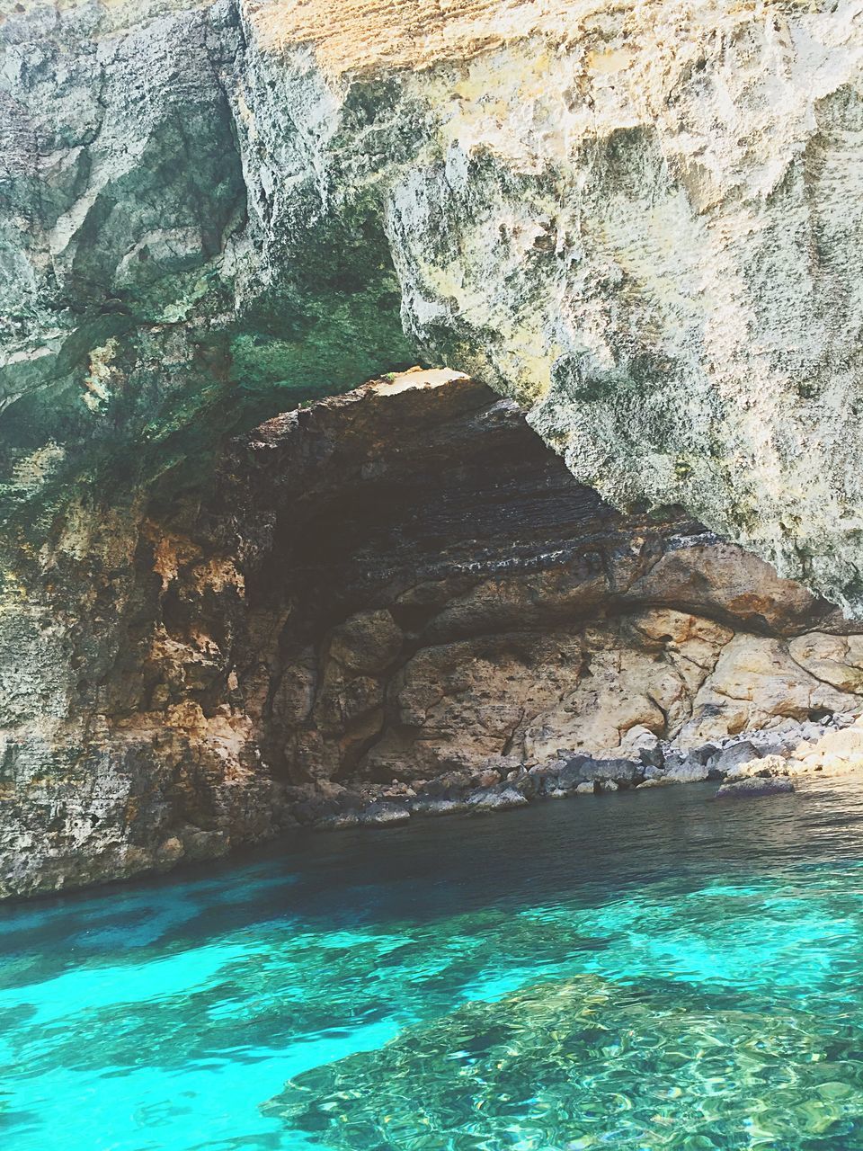 water, rock - object, rock formation, sea, waterfront, nature, beauty in nature, motion, splashing, blue, sunlight, wave, day, surf, cliff, high angle view, scenics, cave, outdoors, rock