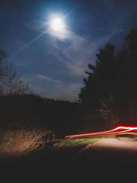 Light trails on road against sky at night