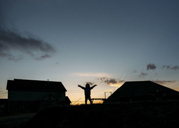 Silhouette of boy standing in backyard against sky