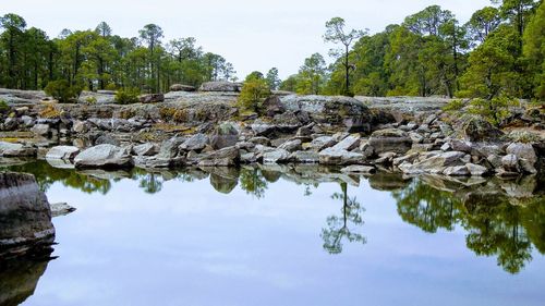 Reflection of rocks in lake against sky