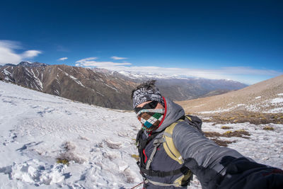 Midsection of person on snowcapped mountain against sky