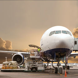 Airplane at airport runway against sky during sunset