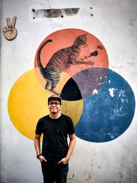 Young man wearing sunglasses standing against wall