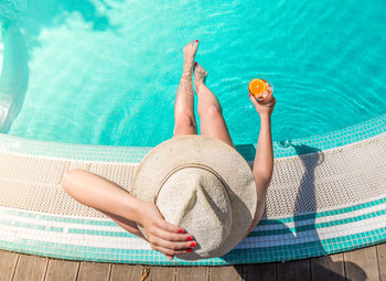 Directly above shot of woman with drink sitting at poolside