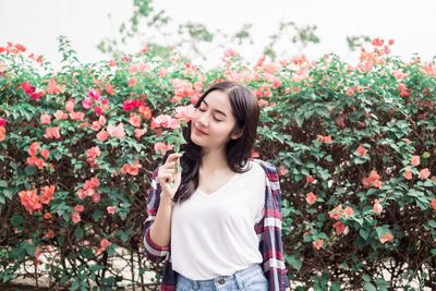 Beautiful young woman standing by flowering plants