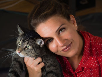 Close-up portrait of smiling young woman holding cat