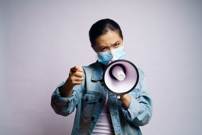 Young women wearing face mask against wall