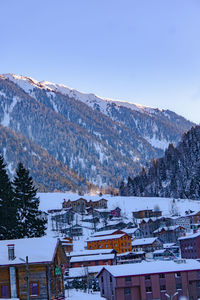 Houses on snowcapped mountain against clear sky